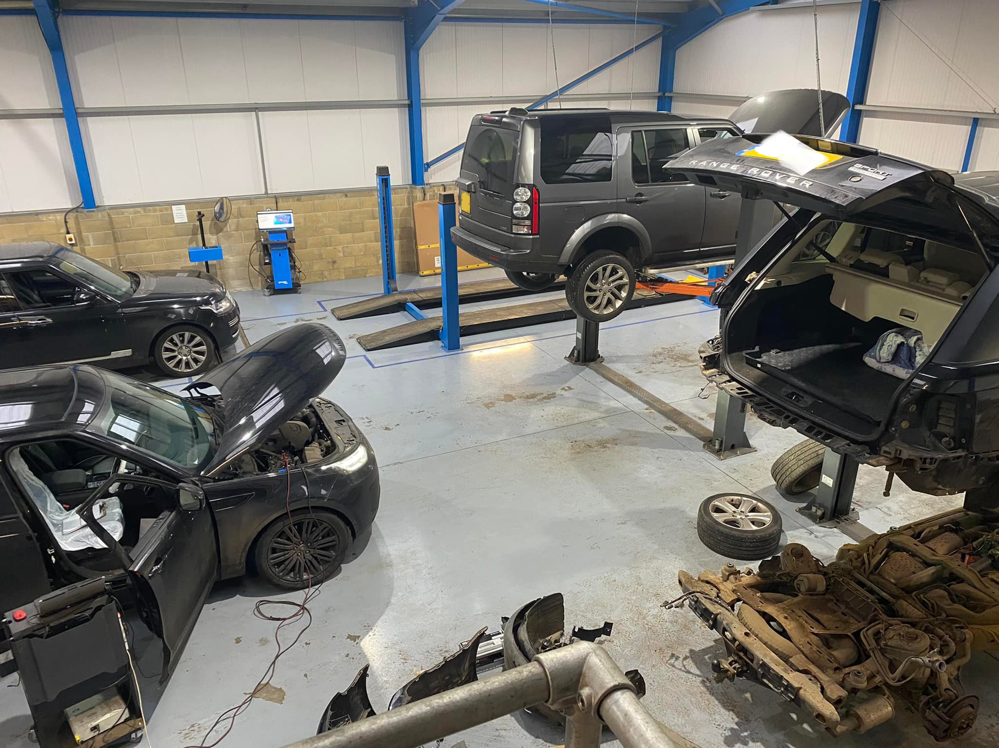 Interior shot of Alan Curtis Land Rover Specialist garage. Several land rovers and range rovers are being serviced or repaired.
