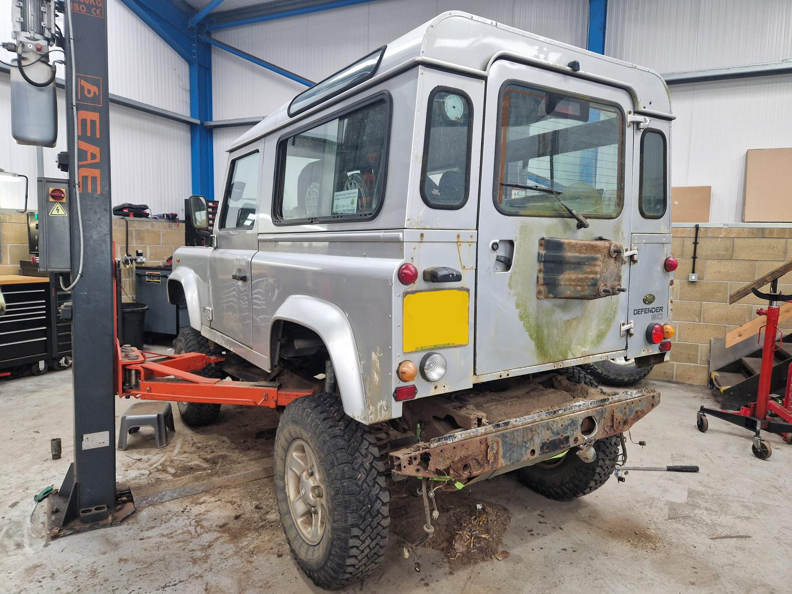 A land rover defender body being removed from its frame by a four point lift.