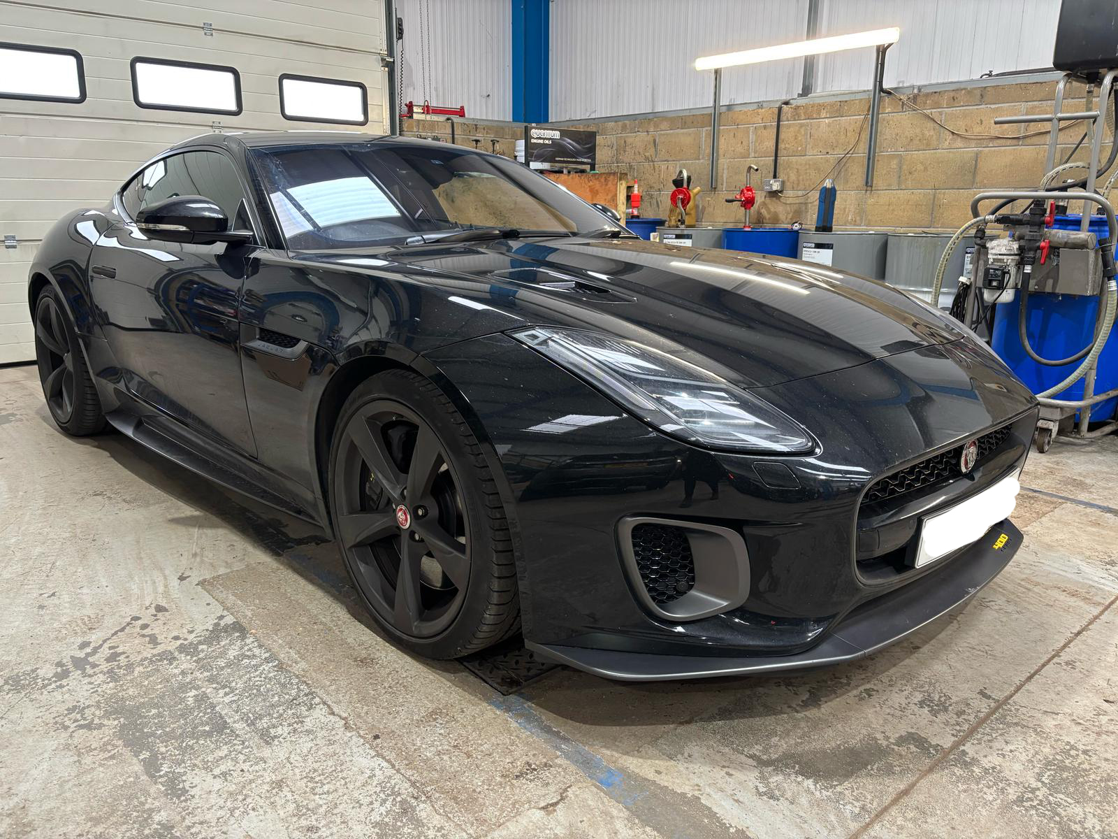 A black jaguar sports car in a mechanics garage
