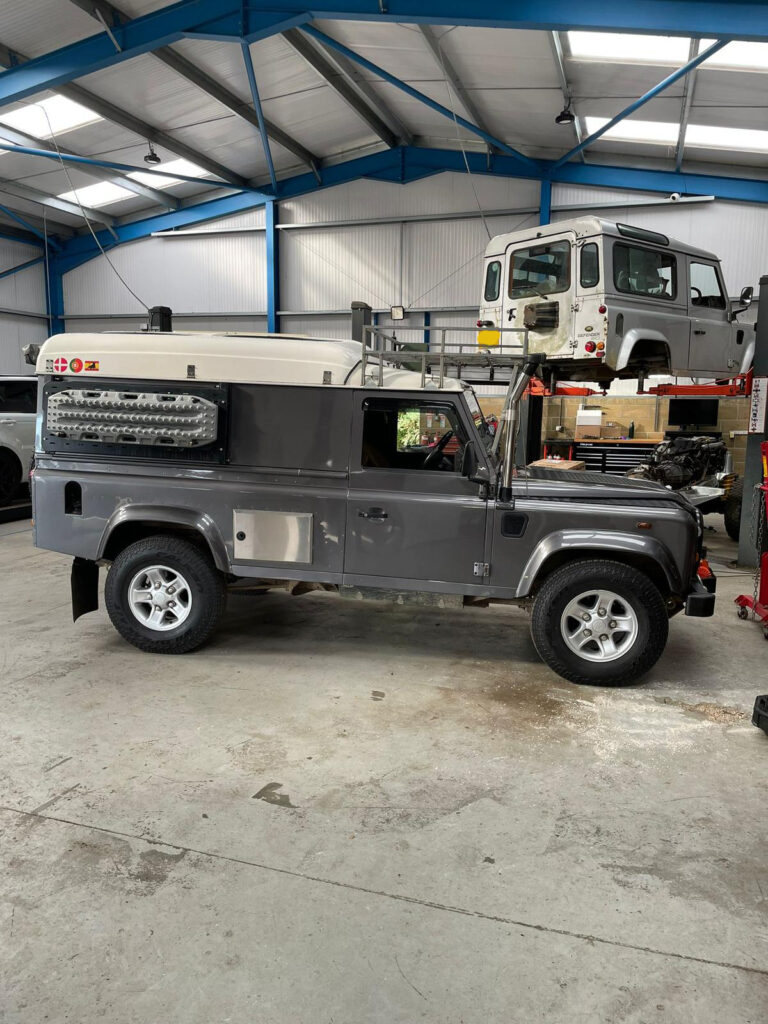 A grey long wheelbase land rover defender in a garage