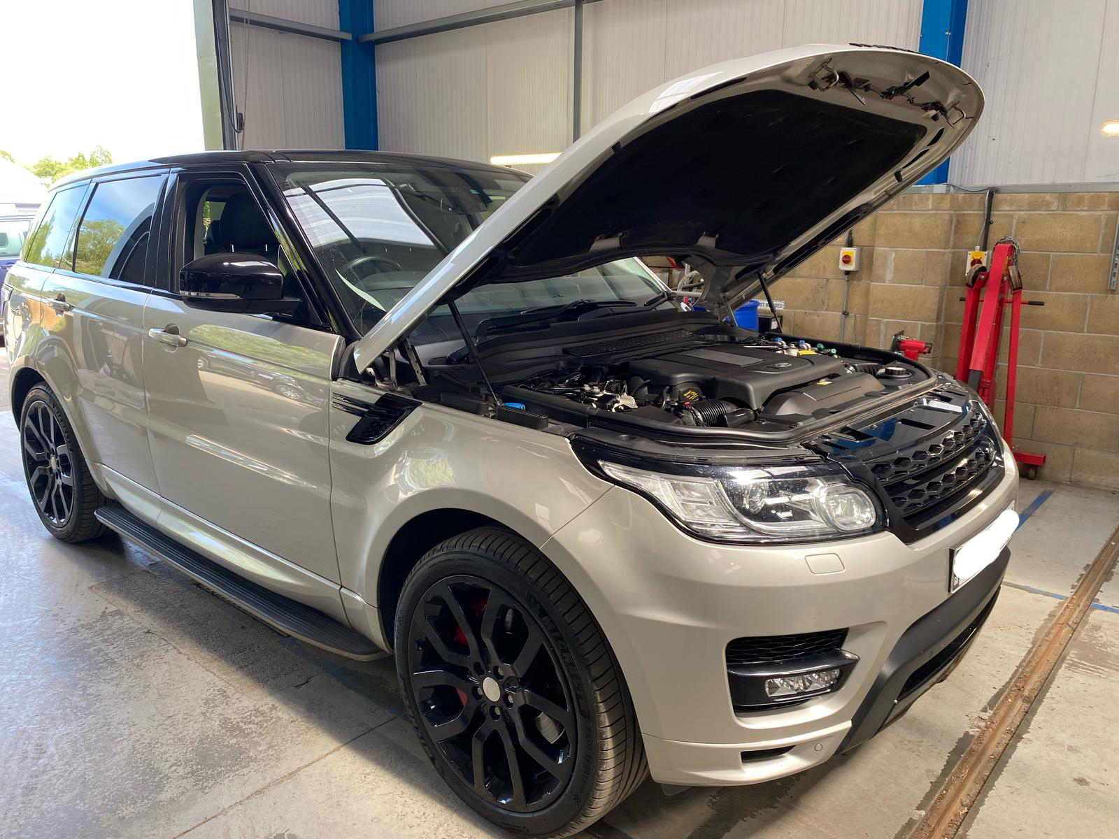 A freshly cleaned silver range rover with its bonnet open.