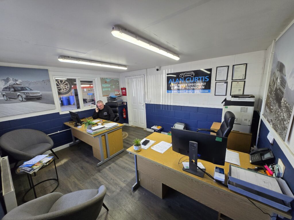 Interior office of Alan Curtis Land Rover Specialist. A staff member talks to a customer over the phone at the far desk.